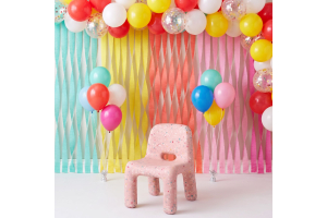 Blush pink recycled plastic kids confetti chair against a vibrant party background.