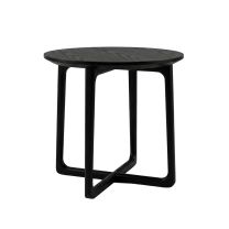 Angled view of the Astrid Round Side Table in black, showcasing the circular top and the sculptural cross-base legs.