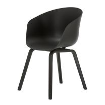 An angled perspective of the all-black Macey dining chair, highlighting the seamless integration between the curved polypropylene shell and the steam-bent plywood legs.