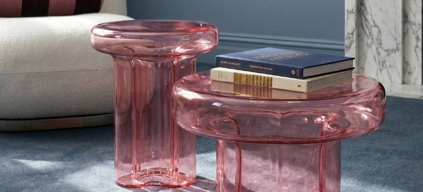 Translucent pale pink hospitality-grade Napier retro glass coffee table and matching side table styled in a soft lighting residential living room with a white boucle armchair.
