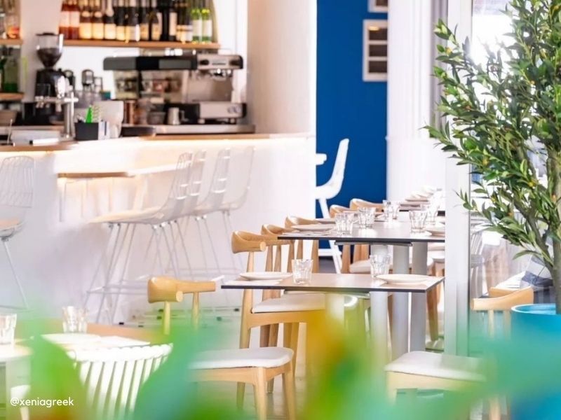 Shop the commercial-grade Replica Elbow Chair. Replica Hans Wegner Elbow Chair with padded seat in a commercial dining setting, highlighting durable timber construction.