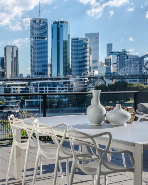 Replica Masters chairs on a Brisbane balcony overlooking the CBD river. Best replica furniture for outdoor living in Queensland.