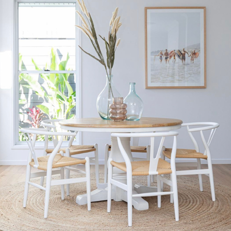 Five Replica Wishbone chairs with white frame and natural cord seat, styled in a home around a timber dining table.