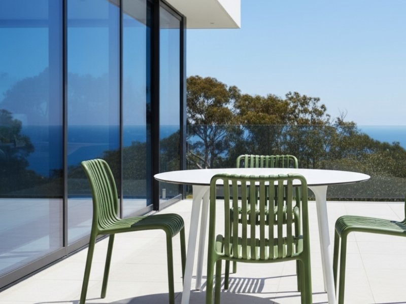 Bordeaux Stacking Polypropylene Outdoor Dining Chairs in olive on a modern Australian deck with ocean view.