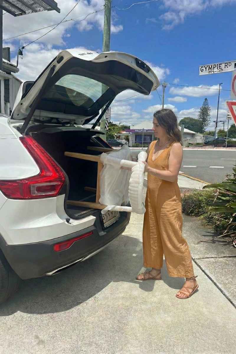 Customer loading a Replica Hans Wegner Elbow Chair into their car to use the 24-hour loan service at Replica Furniture Brisbane.