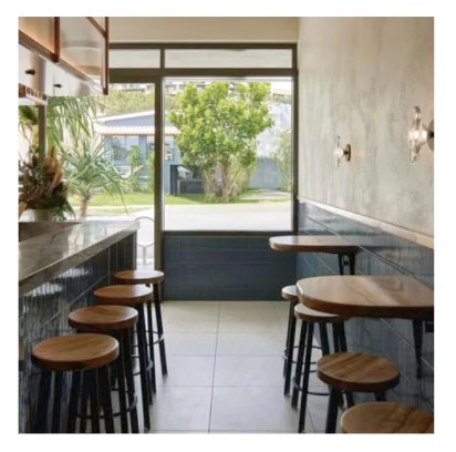 Industrial style timber-seat bar stools with black metal bases along a dark bar counter in a cafe setting