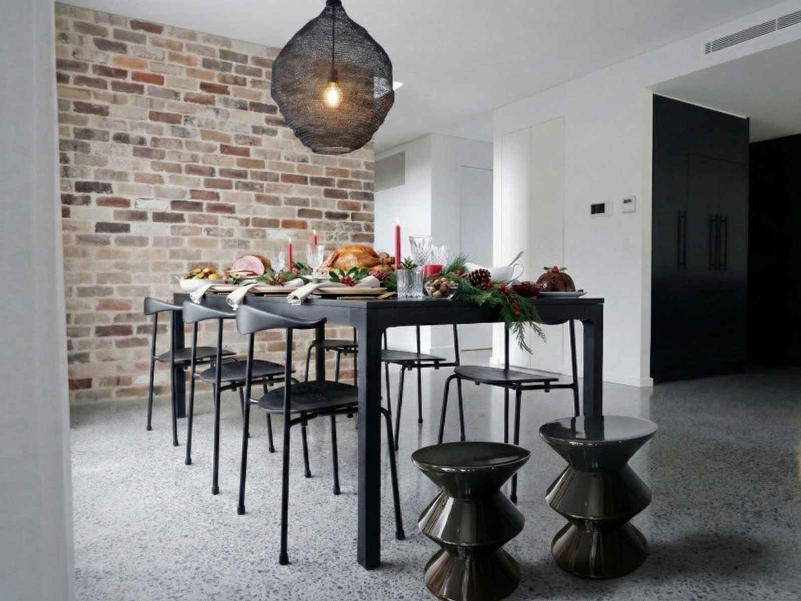 Shop the versatile Replica Hourglass Stool. Cozy living space featuring a rectangular timber table and two black Replica Hourglass Stools, demonstrating versatile extra seating for guests.