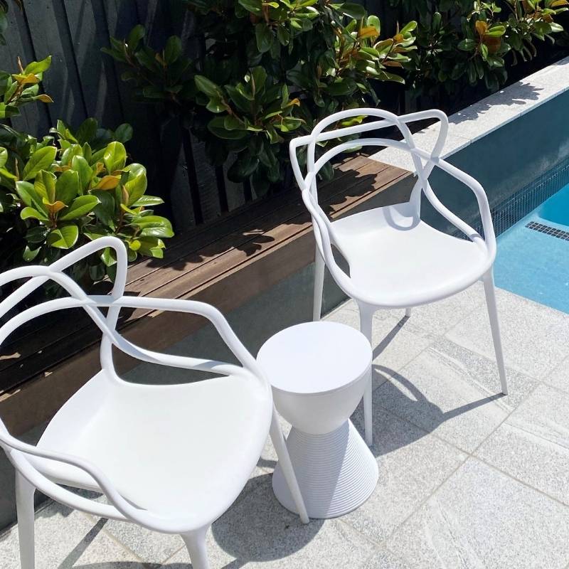 Shop Replica Prince AHA Stools: Versatile Indoor & Outdoor Accents. White Replica Prince AHA Stool serving as a poolside table between two white outdoor chairs in a modern Sydney backyard.