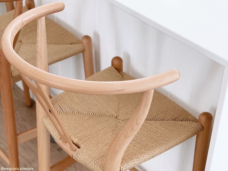 Shop the Replica Wishbone Collection in Natural Timber. Detail of natural timber Replica Wishbone Stool with a woven papercord seat, highlighting material honesty.