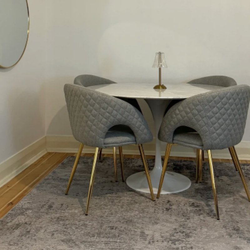 Shop Iconic Marble Tables for Small Apartment Dining. Iconic Replica Tulip Marble Table with quilted grey dining chairs in a small, modern apartment dining nook.